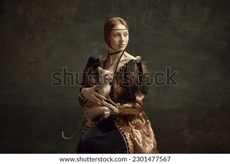 Portrait of pretty young girl in elegant retro clothing over dark vintage background posing with sphynx cat. Lady with ermine remake. Concept of history, renaissance art remake, comparison of eras
