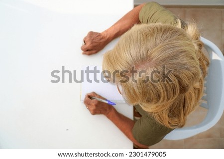 left-handed unrecognizable woman writes in notebook outside. aerial view. international left handers day Royalty-Free Stock Photo #2301479005