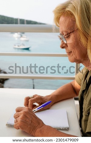 a left-handed lady writes concentrated in the notebook outside. international left handers day Royalty-Free Stock Photo #2301479009