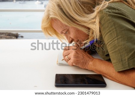 a left-handed woman with mental illness writes concentrated in the notebook outside. mental health. international left handers day Royalty-Free Stock Photo #2301479013