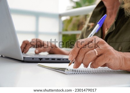 an unrecognizable left-handed woman writes in a notebook outside. international left handers day Royalty-Free Stock Photo #2301479017