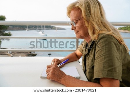 a left-handed lady writes concentrated in the notebook in seascape. international left handers day Royalty-Free Stock Photo #2301479021