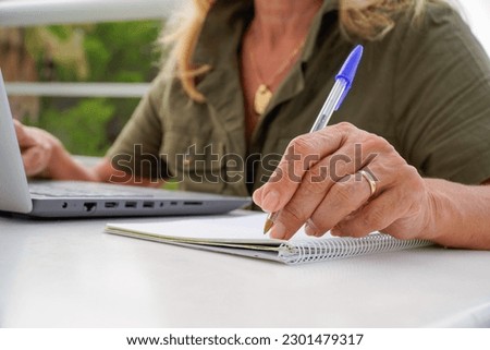 an unrecognizable left-handed woman writes in a notebook outside. international left handers day Royalty-Free Stock Photo #2301479317