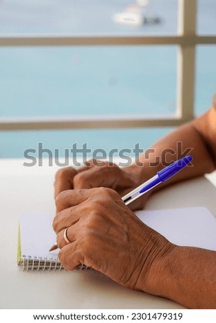 close up of left-handed unrecognizable woman works with the computer and writes in the notebook outside. international left handers day Royalty-Free Stock Photo #2301479319