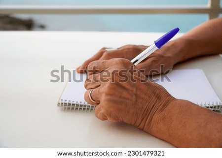 close up of left-handed unrecognizable woman works with the computer and writes in the notebook outside. international left handers day Royalty-Free Stock Photo #2301479321