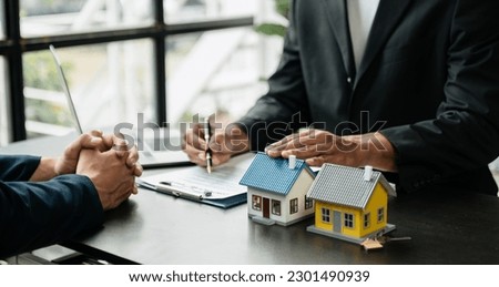 Real estate broker agent presenting and consult to customer to decision making sign insurance form agreement, home model, concerning mortgage loan offer in office