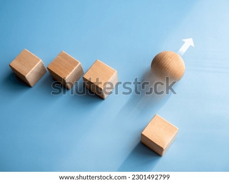 Leadership, business success, unique, difference, challenge, and motivation concepts. Wooden sphere rolling fastest, leading with rising arrow and following with wood cube blocks on blue background. Royalty-Free Stock Photo #2301492799