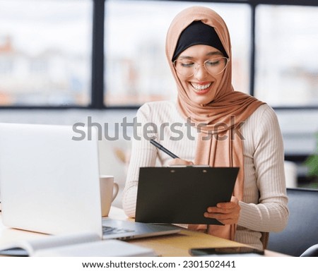 beautiful young smiling muslim woman in traditional religious hijab works remotely on laptop from home
