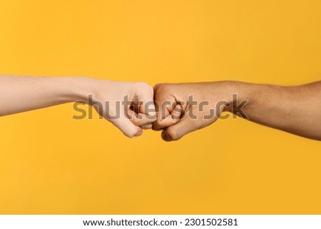 International relationships. People making fist bump on orange background, closeup Royalty-Free Stock Photo #2301502581