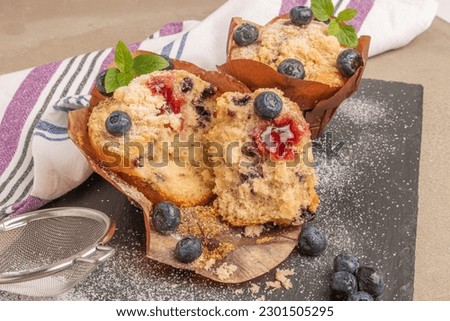 Sweet homemade pastries muffin with blueberries and fresh berries on slate background.