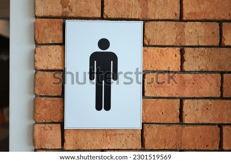 Men's restroom sign symbol on red brick wall.
