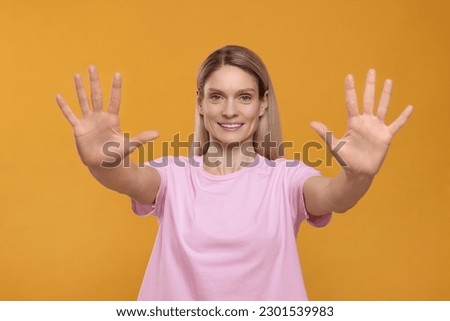 Woman giving high five with both hands on orange background