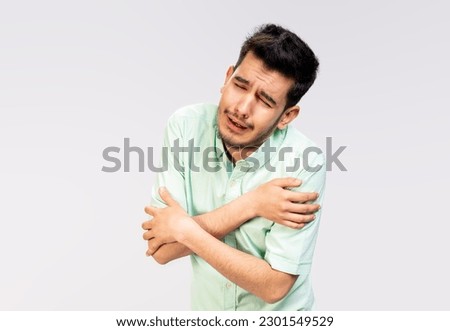 portrait of a young Asian man crying in pain while standing against white background in white shirt and jean pants , negative feeling emotion human