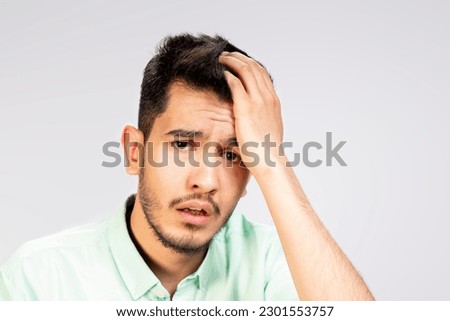 portrait of sad young Asian man holding  his hand to his head due to forgotten , looking shocked and miserable , negative emotion in white shirt isolated on white background Royalty-Free Stock Photo #2301553757