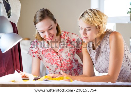 Two young pretty needlewomen in studio working at order