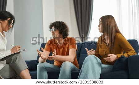 Unhappy couple argues and expresses their relationship problems during a therapy session with psychologist. Marital therapy. Resolving relationship issues Royalty-Free Stock Photo #2301588893