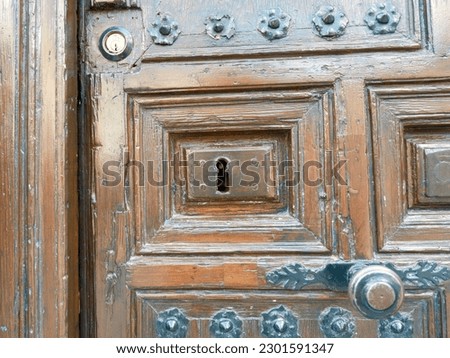 Vintage shabby wooden door of dark brown colour with keyhole and decorative metallic details. Rustic antique entrance.