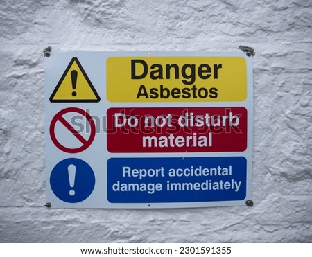 An asbestos warning sign on a white building wall in Scotland