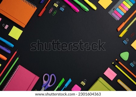 Frame of colorful school and office stationery set on black background. Flatly, copyspace.
