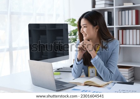 Young businesswoman smiling while resting her chin on her hands, sitting in the office room.