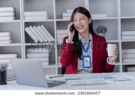 Happy businesswoman talking on mobile phone while analyzing weekly schedule in the office.	
