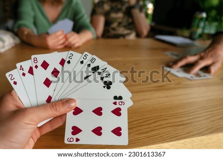 Woman playing with cards with friends close up .