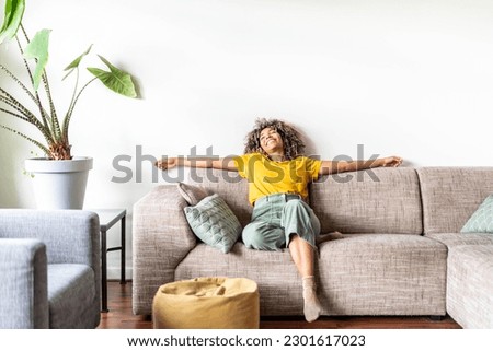 Happy afro american woman relaxing on the sofa at home - Smiling girl enjoying day off lying on the couch - Healthy life style, good vibes people and new home concept Royalty-Free Stock Photo #2301617023