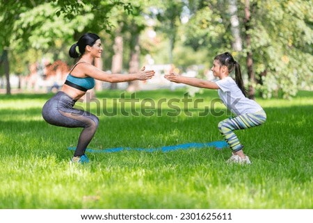 Mom and daughter working out together in city park.