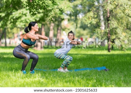 Mom and daughter working out together in the public park.
