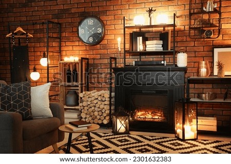 Stylish living room with beautiful fireplace, armchair and different decor at night. Interior design Royalty-Free Stock Photo #2301632383