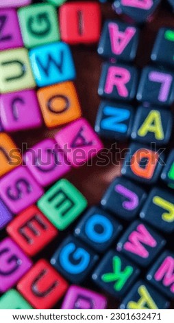 Blurred photo of plastic cubes on wooden table filled with colorful alphabet letters on wooden background.