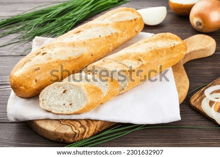 Half an onion baguette on a towel, French bread, wooden background Royalty-Free Stock Photo #2301632907