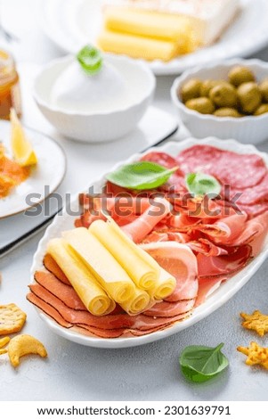 Appetizers with differents antipasti, charcuterie, snacks, meat platter with cheese and spicy olives, salmon carpaccio and tomato salad Royalty-Free Stock Photo #2301639791