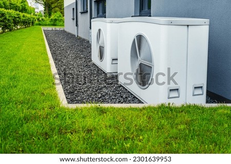 Two air source heat pumps installed outside of new and modern city house, green renewable energy concept of heat pump Royalty-Free Stock Photo #2301639953