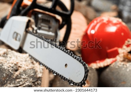 Modern chain saw and  firewood,closeup Royalty-Free Stock Photo #2301644173