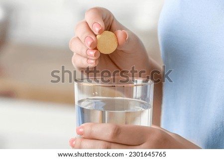 Woman putting effervescent tablet into glass of water, closeup Royalty-Free Stock Photo #2301645765