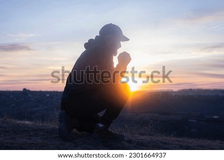 Prayer. Man on his knees praying. On the background of the sunset sky. Kneeling Prayer to God. Worship and praise. Royalty-Free Stock Photo #2301664937