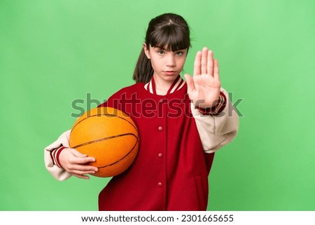 Little caucasian girl playing basketball over isolated background making stop gesture