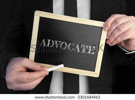 A businessman holds up a chalkboard with text Advocate