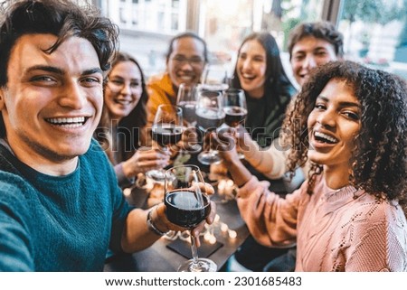 Multiracial friends drinking and toasting red wine at bar table- Group of happy young people taking selfie picture at restaurant-Life style concept with youth guys enjoying happy hours