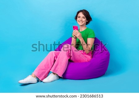 Full length photo of sweet pretty woman dressed green top sitting bean bag texting device empty space isolated blue color background