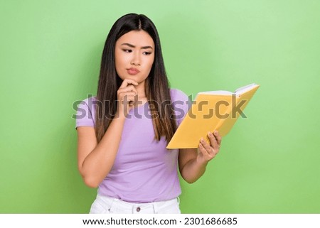 Photo of lovely young vietnamese chinese lady hold read book unsure dressed stylish violet garment isolated on green color background