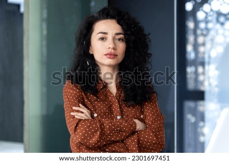 Portrait of mature female boss inside office building, successful hispanic woman looking serious at camera with crossed arms, businesswoman confident. Royalty-Free Stock Photo #2301697451