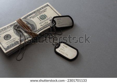 The soldier's military tokens are on dollar bills. Concept: cost of living soldier, military pensions, soldiers of fortune and mercenary Royalty-Free Stock Photo #2301701133