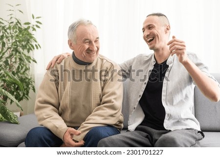 Young adult caucasian son listening and supporting his old elderly senior father at home indoors. Care and love concept. Royalty-Free Stock Photo #2301701227