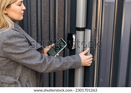 female entering secret key code for getting access and passing building using application on mobile phone, woman pressing buttons on control panel for disarming smart home system Royalty-Free Stock Photo #2301701263