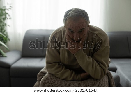 Frustrated unhappy middle aged mature man sitting on sofa, feeling depressed alone at home. Confused senior retired grandfather worrying about difficult life decision, copy space, old people solitude Royalty-Free Stock Photo #2301701547