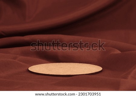Wooden circle disk platform podium on brown silk fabric background. Minimal empty display product presentation scene.