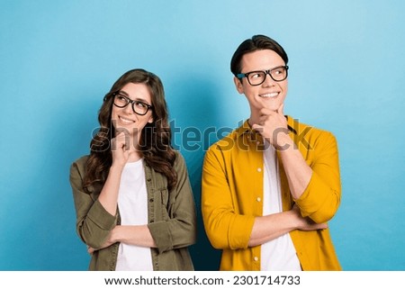 Photo of dreamy funny married couple wear shirts spectacles looking empty space arm chin isolated blue color background