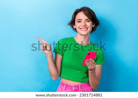 Photo of adorable cute lady dressed green top pointing empty space chatting modern device isolated blue color background
